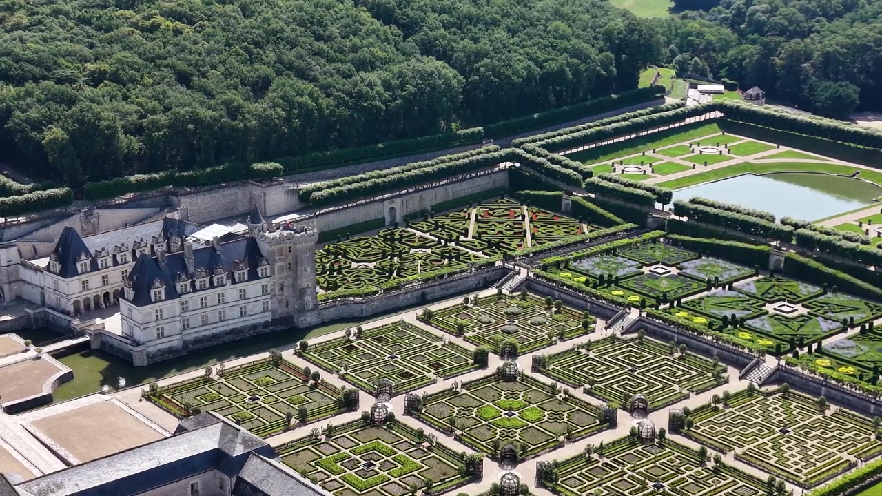 Veduta aerea cinematografica con drone del Castello di Villandry che domina i suoi rinomati giardini rinascimentali, caratterizzati da intricati disegni di parterre, siepi ornamentali, giardini acquatici e la tenuta circostante.