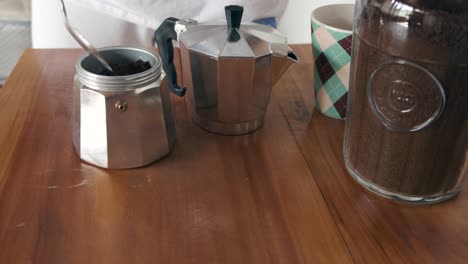 preparing a moka pot with ground coffee on wooden surface