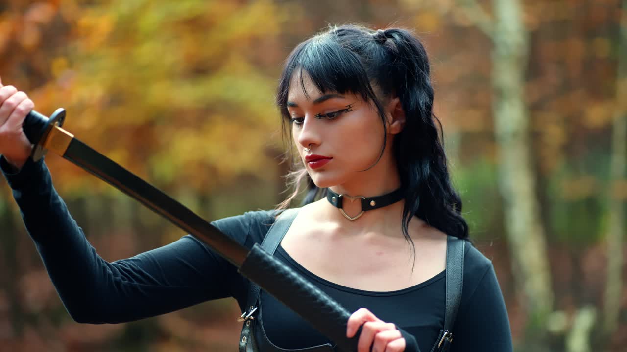 la chica de negro examina una espada japonesa, una katana