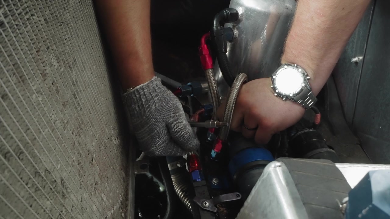 Mechanic Tightening Hoses in a Car Engine Bay