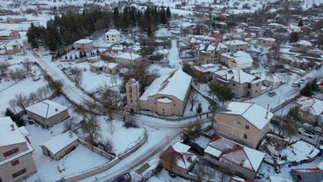 Old-church-in-the-center-of-touristic-village-of-Voskopoja-in-Albania,-covered-in-white-snow-at-winter
