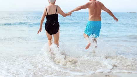 una pareja feliz corriendo hacia el agua