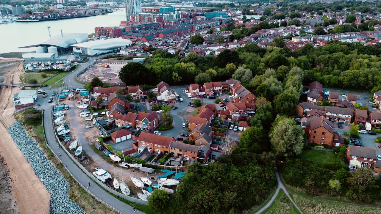 Aerial drone pans right over Weston Southampton, capturing autumn trees and shoreline bathed in warm sunset light, with a tranquil coastal scene highlighted by golden reflections