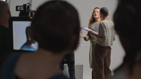 Rear-View-Of-Film-Crew-Shooting-Movie-Or-Video-In-Studio-With-Female-Director-Talking-With-Actors-In-Rehearsal-4