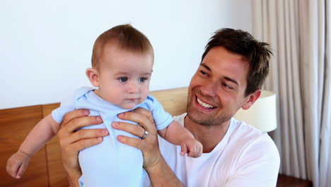 padre feliz sentado con el bebé hijo en la cama