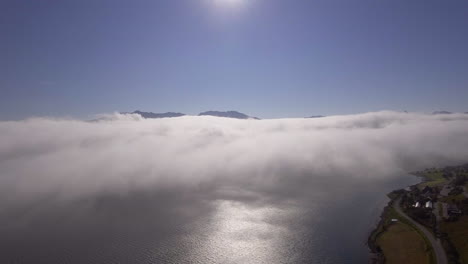 aerial of clouds drifting over a fjord