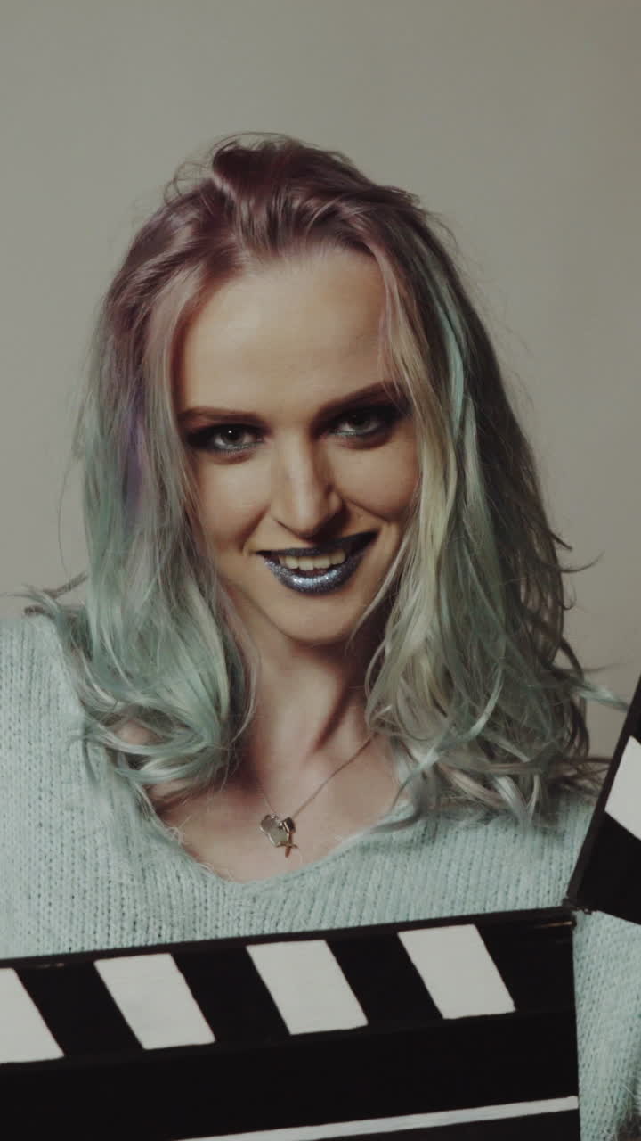 Woman playing with a clapboard. Portrait of a happy woman playing with a clapboard in studio