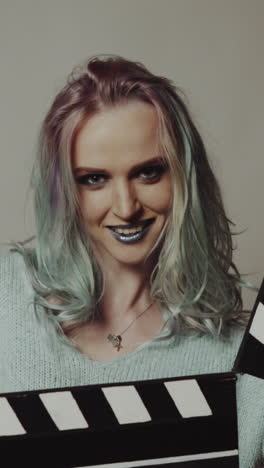 woman playing with a clapboard. portrait of a happy woman playing with a clapboard in studio