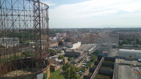 aerial drone forward moving shot flying beside an old unkept iron structure, gazometro in ostiense district, rome, italy at daytime