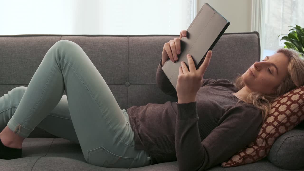 Slider shot of a young Millennial woman looking at her tablet