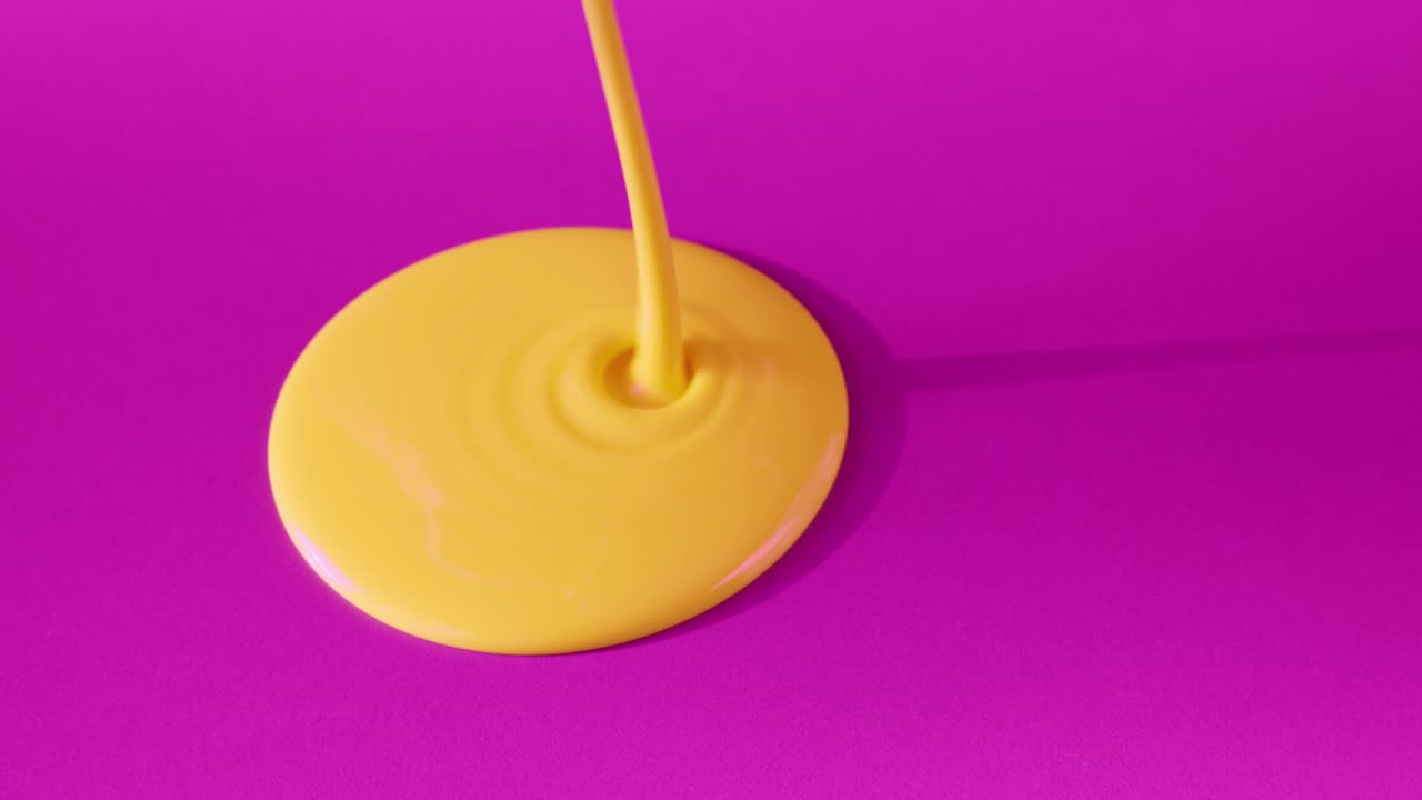 Gota de pintura amarilla sobre fondo morado
