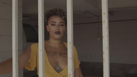young woman wearing a yellow dress walking towards while being behind rusty bars