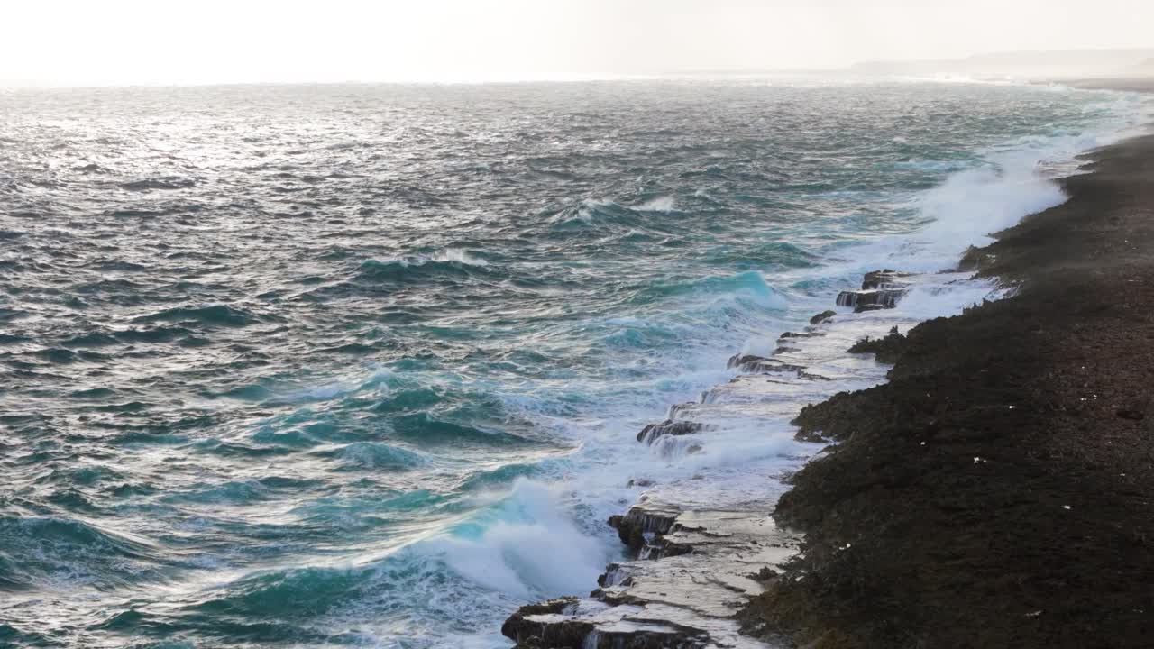 la niebla de pulverización del océano se eleva de las fuertes olas del océano que se estrellan brillantemente a través de la roca de carbonato erosionada en la isla.