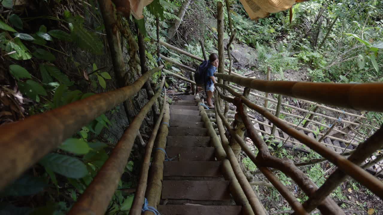 동남아시아의 정글에서 나무 계단을 내려가는 모험적인 소녀