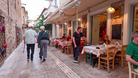 diners enjoy greek food al fresco city quaint streets, handheld walk shot