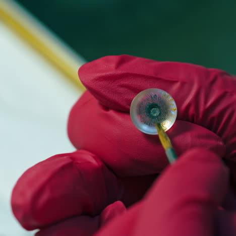 manufacturing of the eye prosthesis. doctor's hands in red gloves making eye prosthesis. close-up.