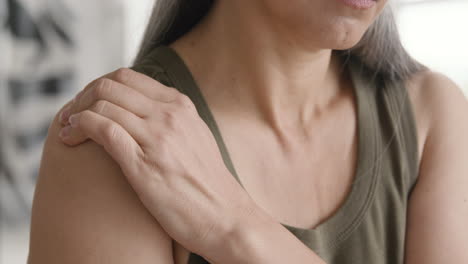 close up of a middle aged woman touching her painful shoulder