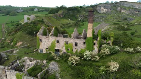 abandoned overgrown ivy covered desolate countryside historical welsh coastal brick factory mill aerial view fast orbit to left front