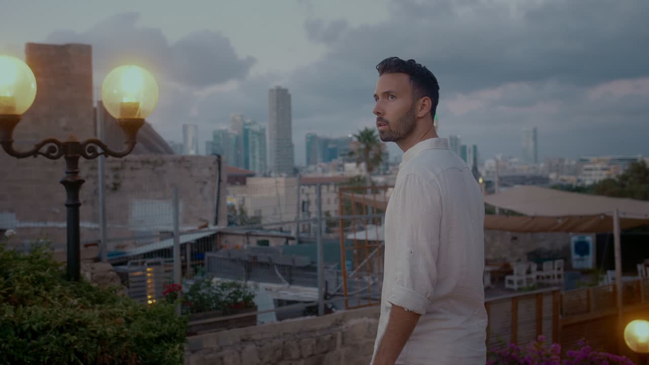 hombre árabe en una camisa absorto en el punto de vista de la ciudad vieja de jaffa al atardecer
