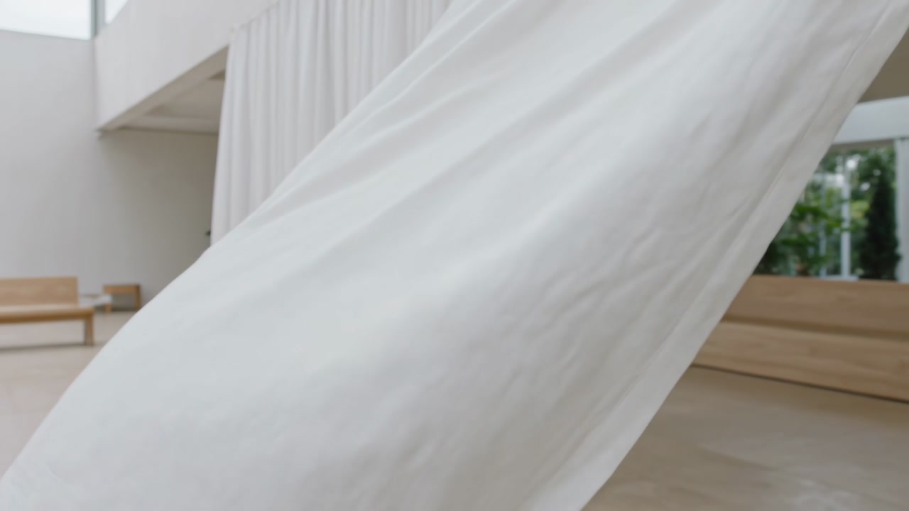 Large white fabric sweeping diagonally through home design space being pulled hiding bench window