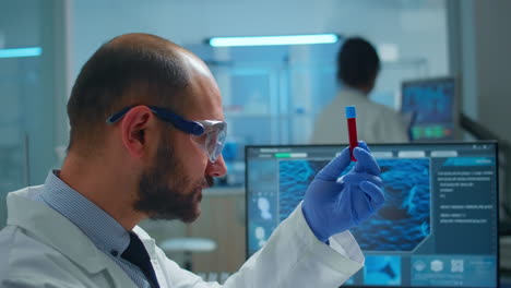 investigador viorólogo examinando una muestra de sangre de un tubo de ensayo