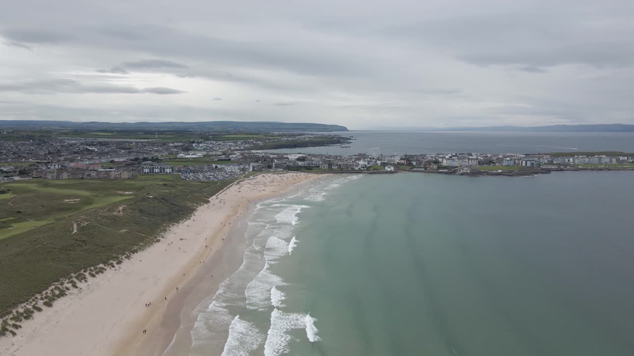 impresionante paisaje de la ciudad costera y la playa de whiterocks de portrush con olas oceánicas en portrush, irlanda del norte - drone aéreo