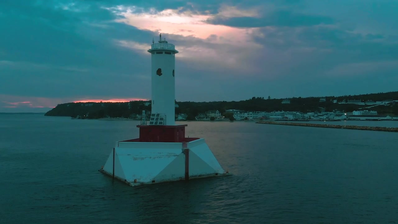 Cảnh quay flycam ngọn hải đăng trên hồ lúc hoàng hôn với bầu trời ráng chiều.