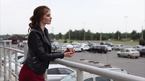 young woman with coffee in a parking lot