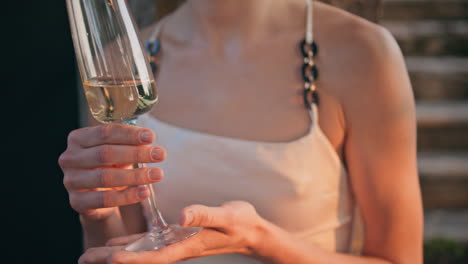 woman hands holding wineglass with refined alcohol drink outdoors close up.