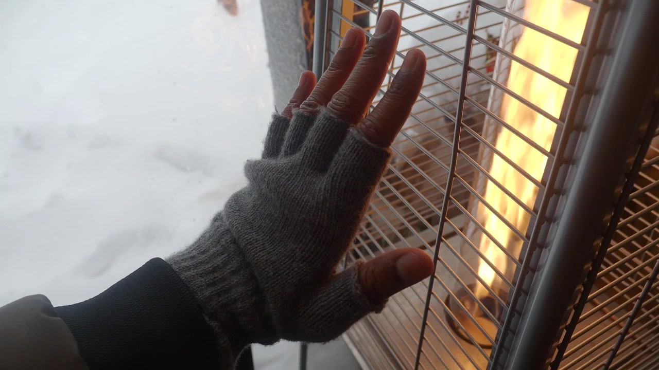 Hand in Fingerless Glove Warming by Outdoor Heater in Winter