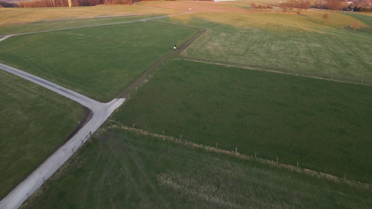 Person sitting on his white scooter in a lush field during sunset