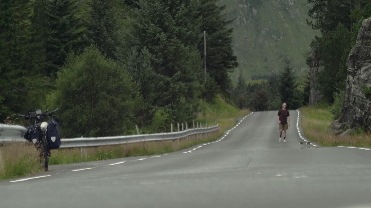 Giovane skateboarder maschio caucasico che tenta e fallisce un kickflip su una strada remota in Norvegia, Scandinavia