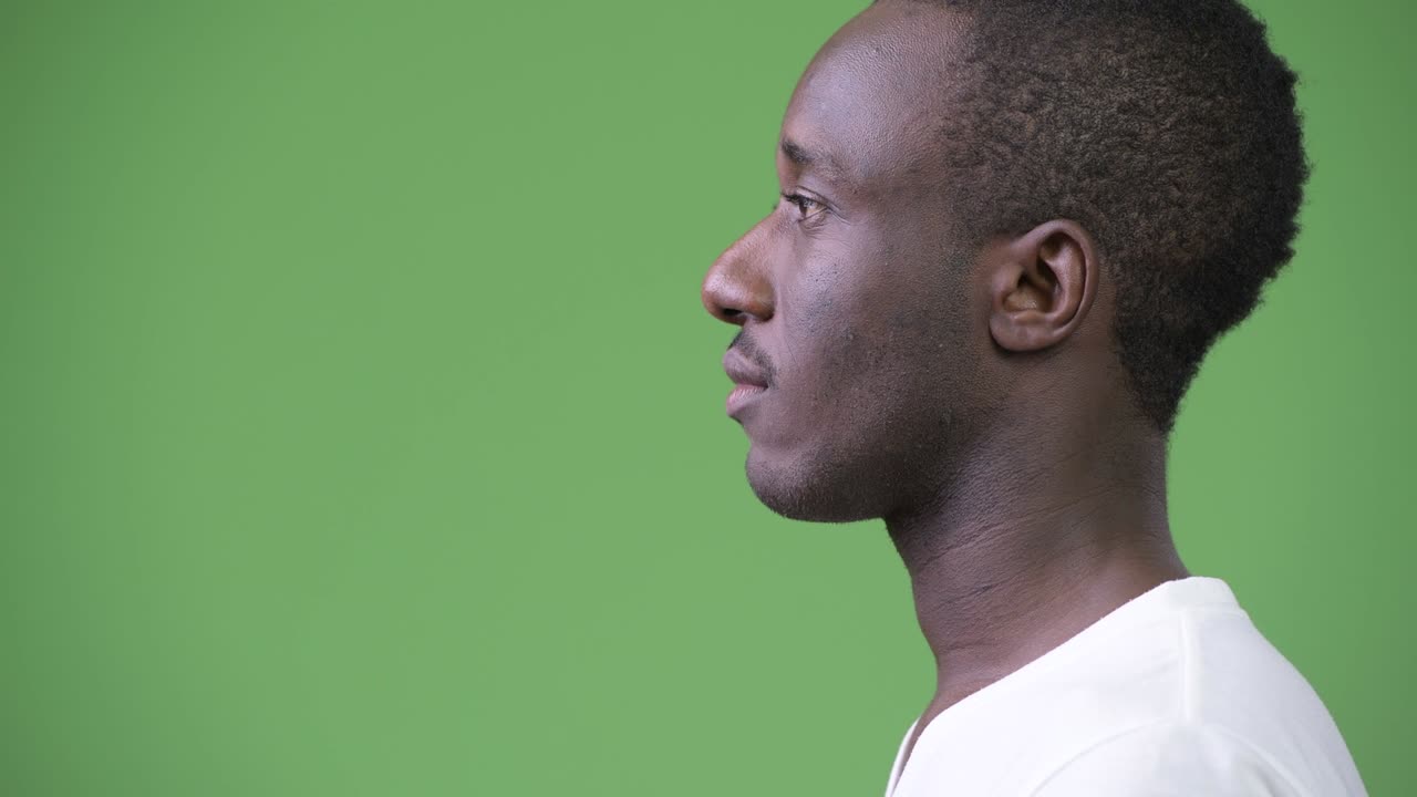 Profile view of young African man against green background
