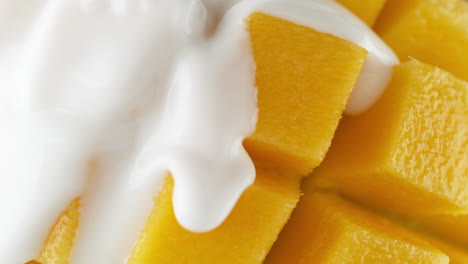 verter yogur sobre la fruta de mango cortada en rodajas y en cubitos (erizo) en cámara lenta