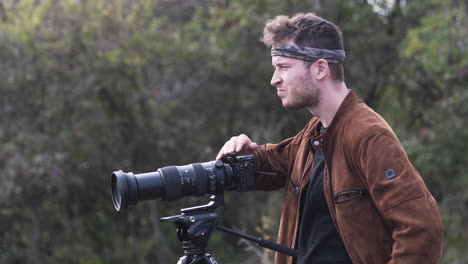 joven fotógrafo de vida silvestre con una cámara trípode dslr mirando a su alrededor