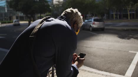 Hombre-Mayor-Afroamericano-Con-Mascarilla-Usando-Un-Teléfono-Inteligente-En-La-Carretera