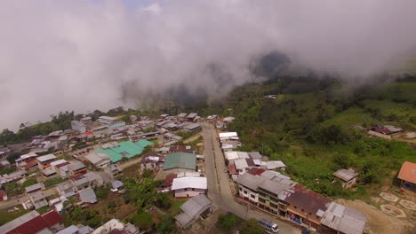 Fly-over-Ecuadorian-town-with-misty-mountain-river-in-distance