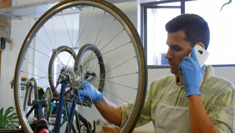 man talking on mobile phone while repairing bicycle 4k