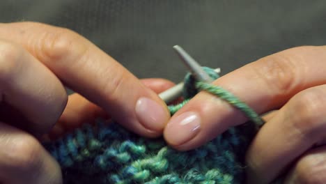 female fingers knit a scarf close up under warm electric light