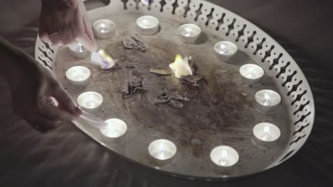 burning paper on a tray with candles