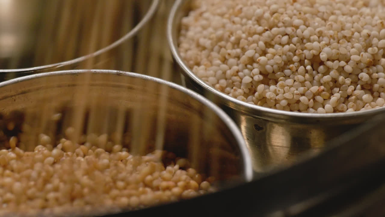 filling barnyard millet in steel bowl with little millet in the background for storage, 4k, close up, stable shot