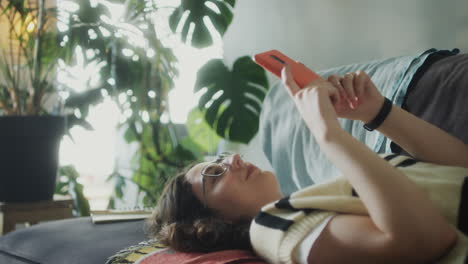 girl lying on sofa and using smartphone