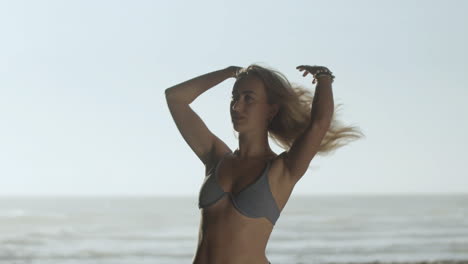 Attraktives-Mädchen-Im-Bikini,-Das-Am-Strand-Haare-Glättet