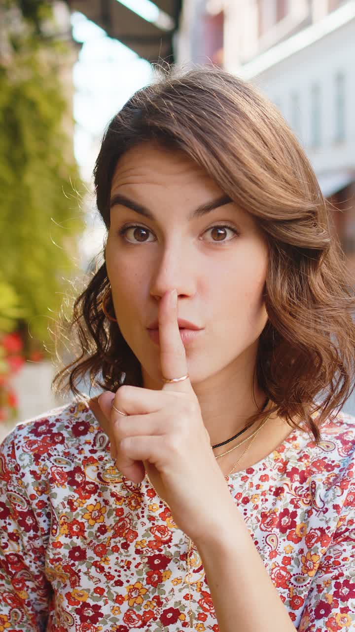 Giovane donna preme il dito alle labbra fa silenzio segno di silenzio non dice pettegolezzi segreto silenzio in città