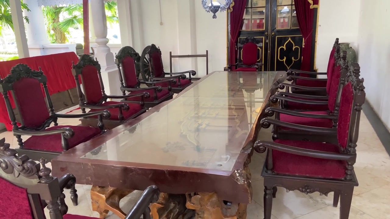 Comedor elegante con mesa de madera ornamentada y sillas de terciopelo rojo
