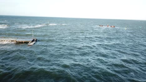 Drone-aerial-spin-shot-over-ocean-Melbourne-wavy-windy-cloudy-person-swimming