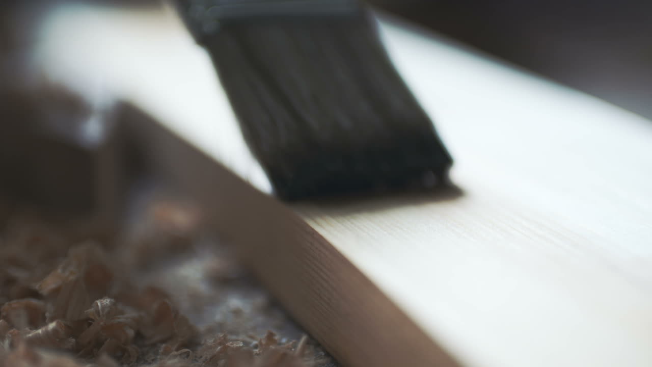 갈색 페인트로 나무 판자를 칠하는 청년 2