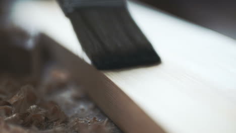 young man painting wooden board with a brown paint 2