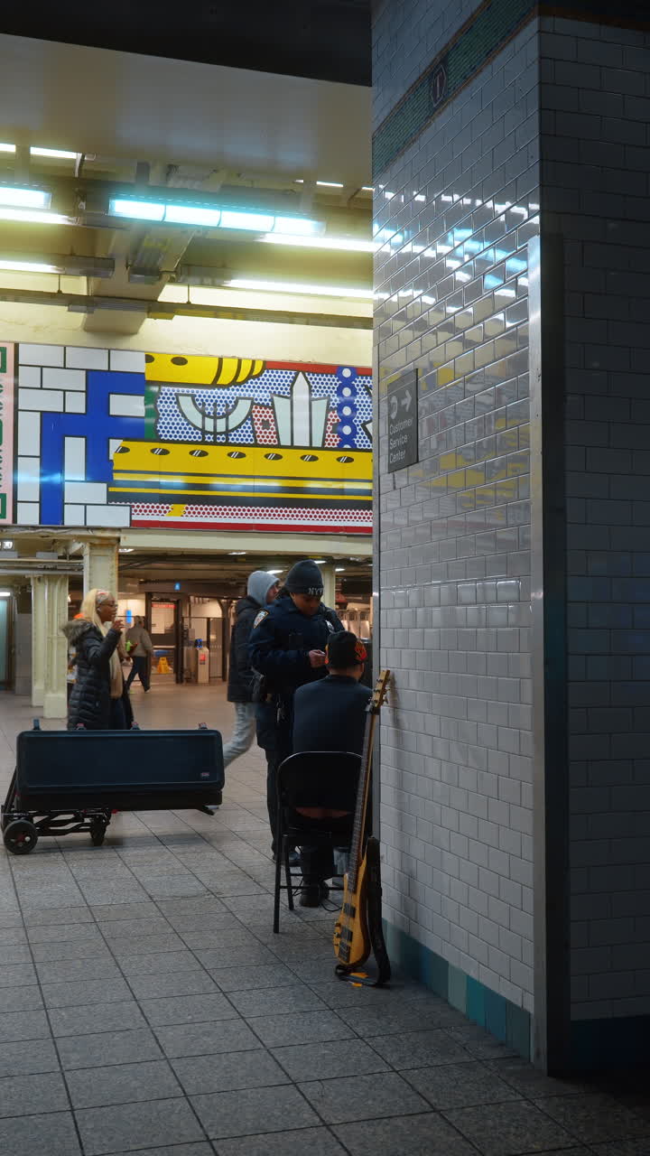 New York, USA, 2 March 2026: Police officer talking to street musician in New York subway. Law enforcement officer interacting with a bass guitar player in a tiled underground station