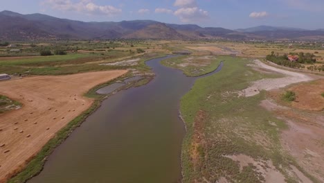 aerial: a river delta with a road-bridge passing through and some agricultural buildings